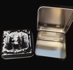 Metallic tin with a black and white witch design on a wooden surface