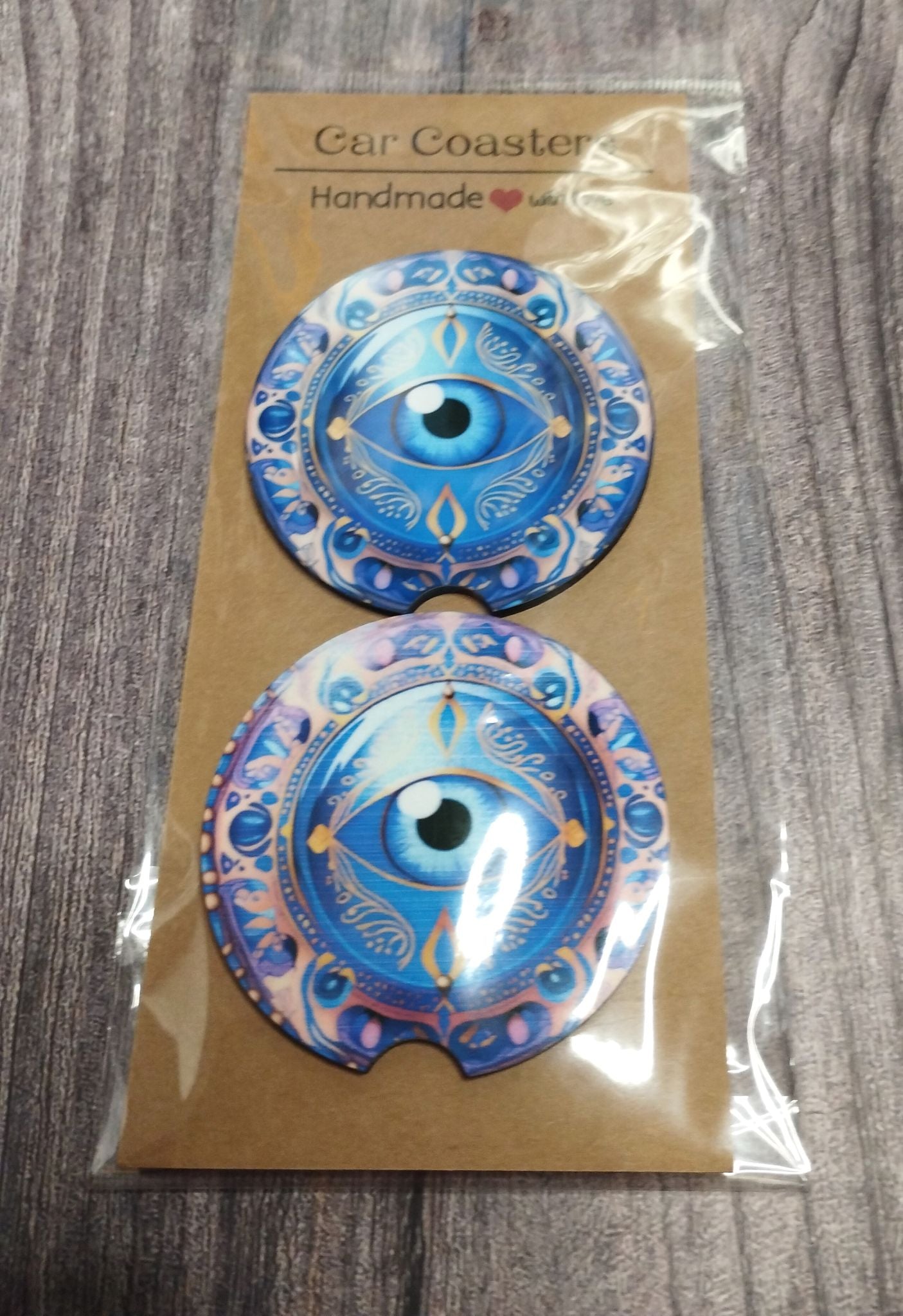 Two blue car coasters with eye design on a brown card packaging.