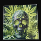 Decorative tile with a skull design and cannabis leaves on a wooden surface