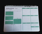 Weekly planner with green highlights on a wooden surface