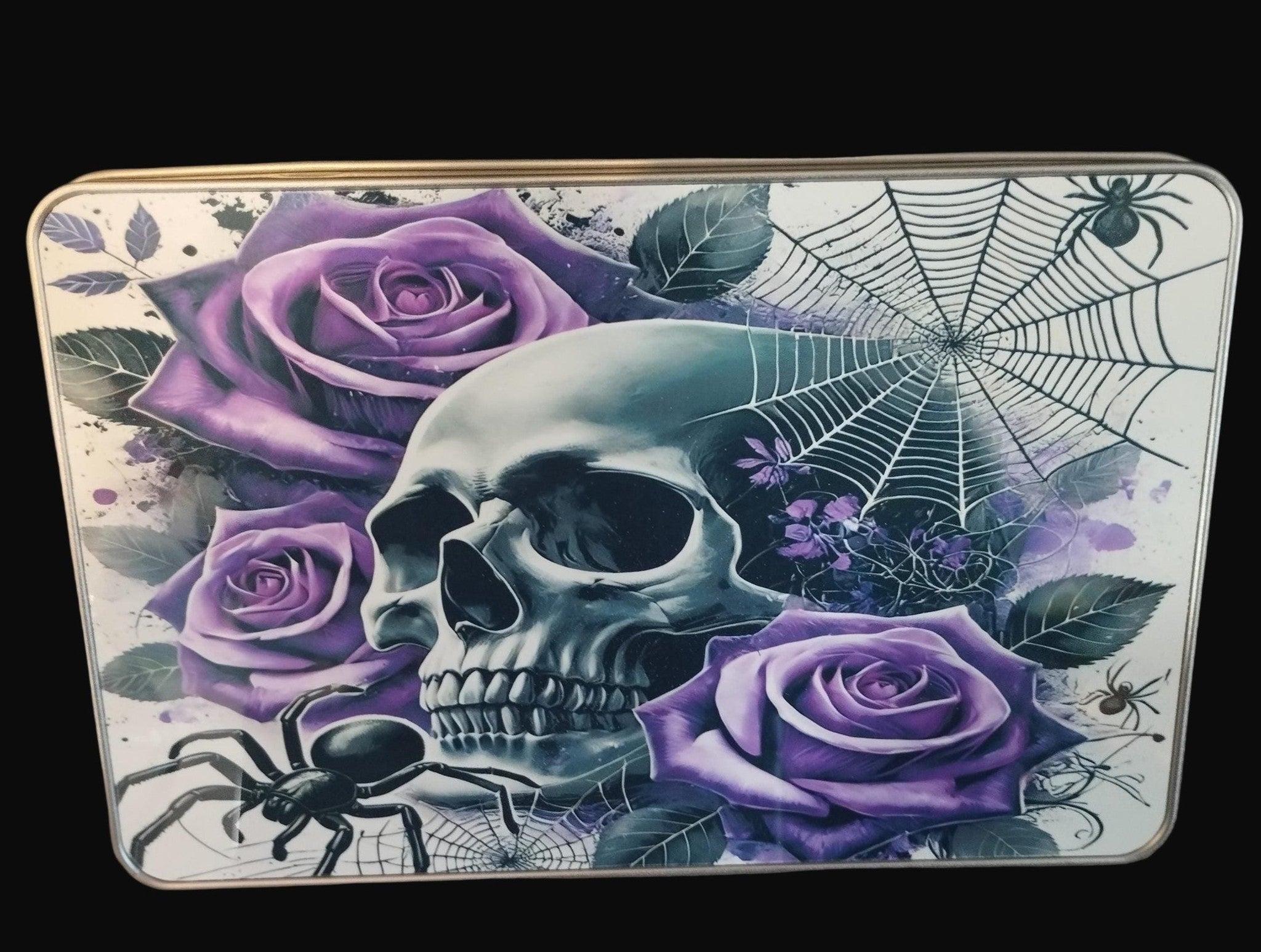 Decorative tin with skull, purple roses, and spider web design on a wooden surface.
