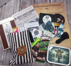 Mystery horror film box with various items including a newspaper, snacks, and a striped bag on a wooden surface.