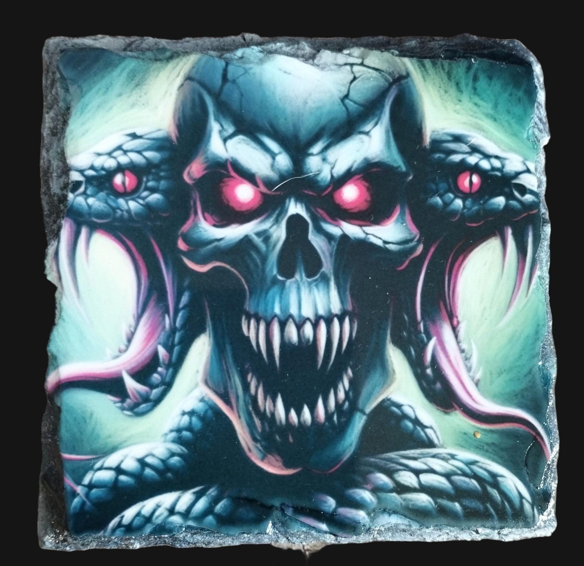 Decorative stone with a skull and snake design on a wooden surface