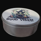 Round metal tin with a witch illustration and 'Casting Spells for Good Vibes!' text on a wooden surface.