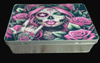 Metal tin with a colorful design of a skull and roses on a wooden surface
