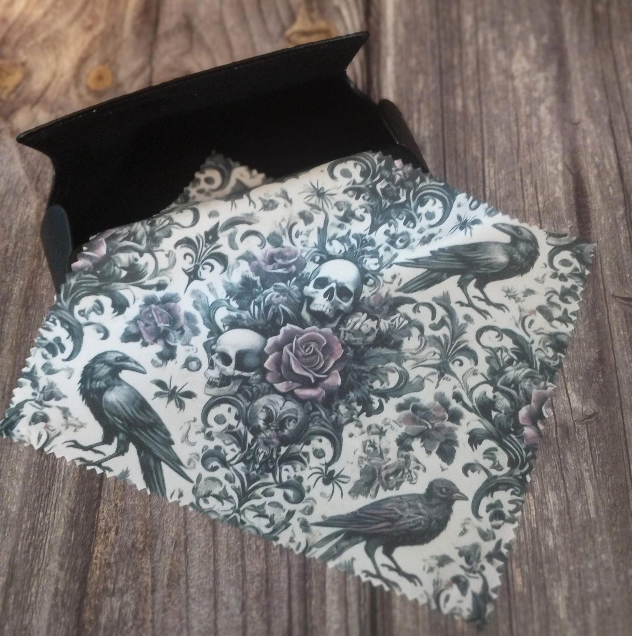 Decorative lens cloth with skull and rose design on a wooden surface