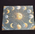 Celestial lens cloth with golden and silvery moons, stars and radiant detailing on a dark background