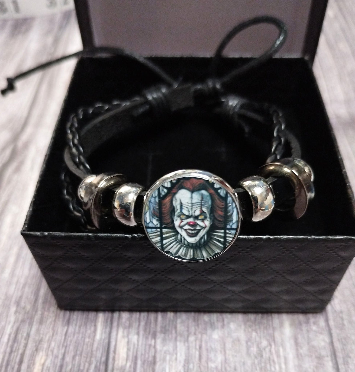 Horror clown bracelet on wooden surface