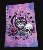 Notebook with a cat, skull, and roses design on a purple and pink gradient background.