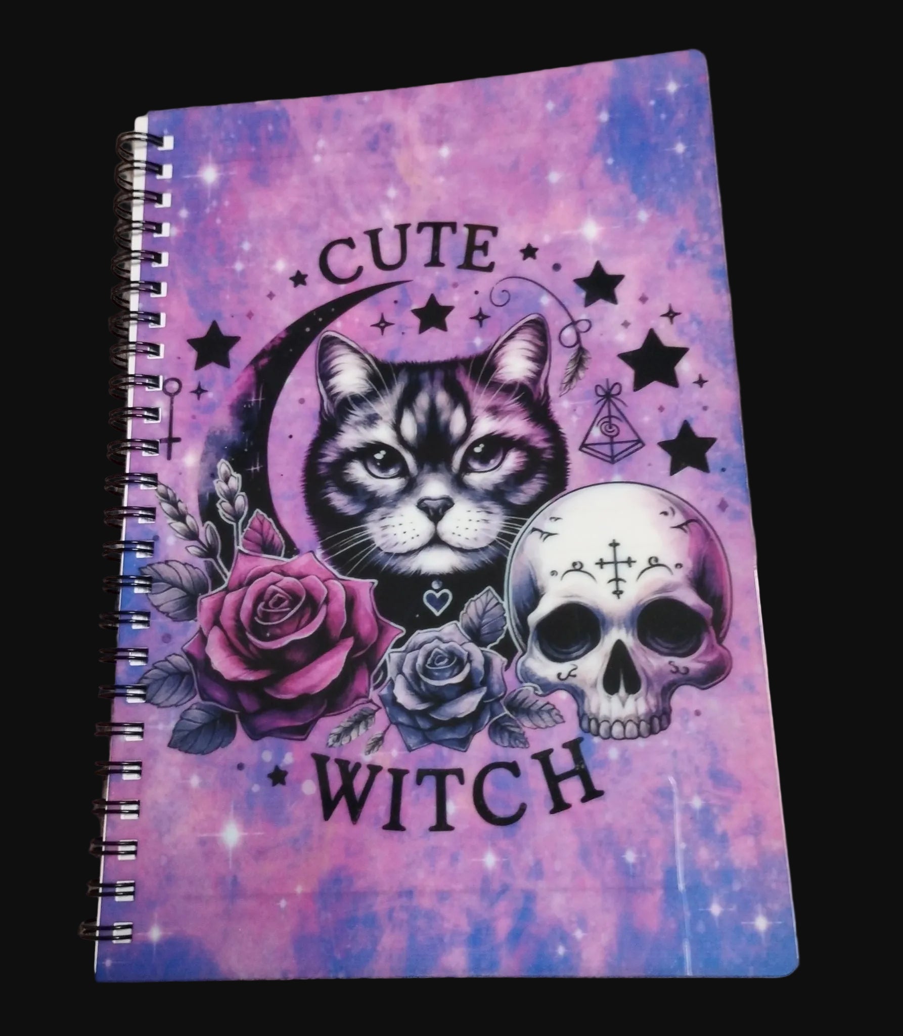 Notebook with a cat, skull, and roses design on a purple and pink gradient background.