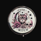 Compact mirror with a cat, skull, and roses design on a wooden surface