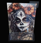 Framed artwork of a woman with skeleton makeup and floral elements.