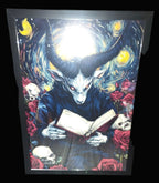 Framed artwork of a creature with horns reading a book against a starry night sky.