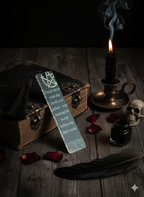 Book with a bookmark, candle, inkwell, and feather on a wooden surface with a dark background.