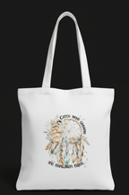 White tote bag with a dreamcatcher design and text on a black background