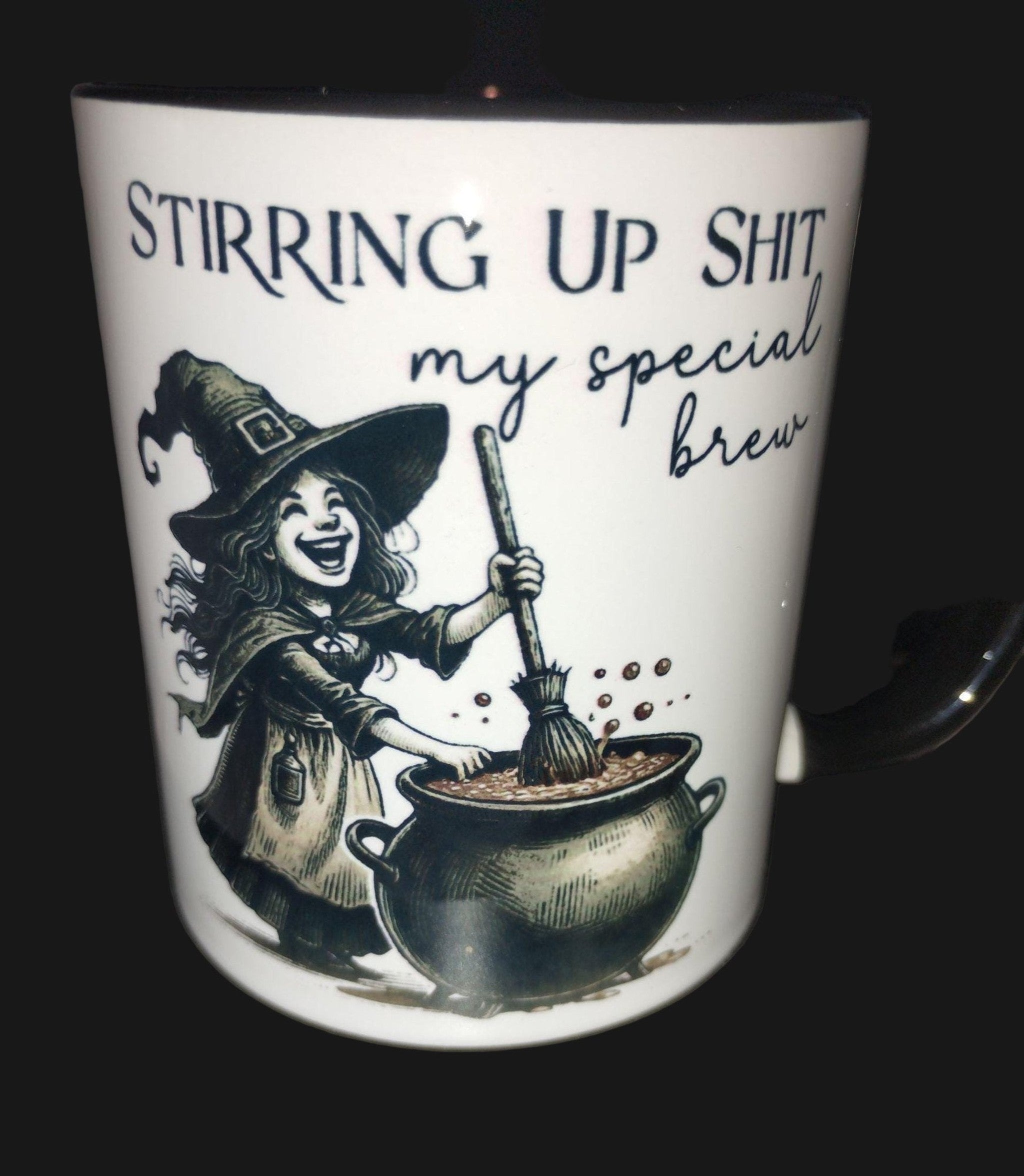 Mug with witch illustration and text 'Stirring up shit, my special brew' on a dark surface.