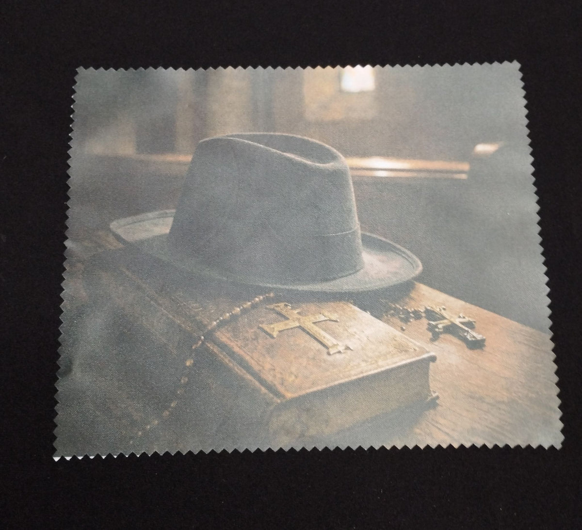 Gothic lens cloth with zigzag edges featuring a black hat, an aged book and crosses in a shadowy scene