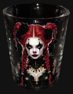 Black shot glass with a colorful design of a woman with red hair and black eyes on a dark background