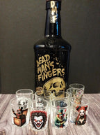 Bottle of Dead Man's Fingers rum with shot glasses featuring various designs on a wooden surface.