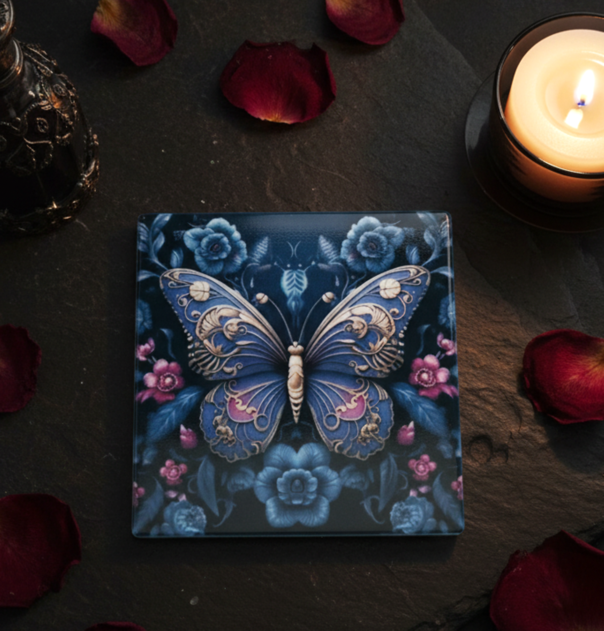 Decorative box with butterfly design on a dark surface with candles and rose petals.