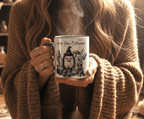 Person holding a mug with steam. The mugs has a hedgehog wearing a witch's hat and the writing says 'Herb your enthusiasm'
