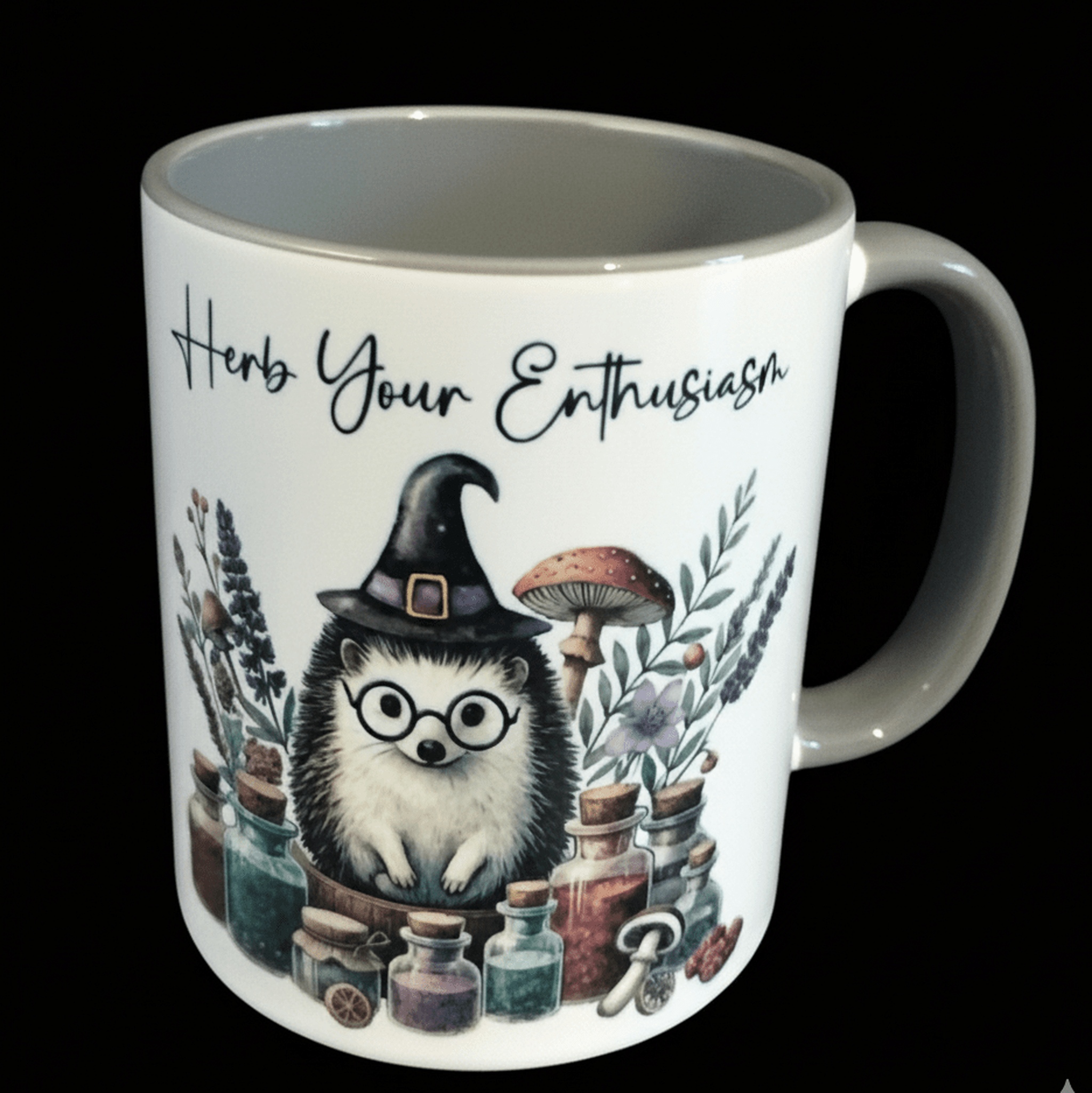 Mug with hedgehog wearing a witch hat and glasses, surrounded by plants and potions, with text 'Herb Your Enthusiasm'.