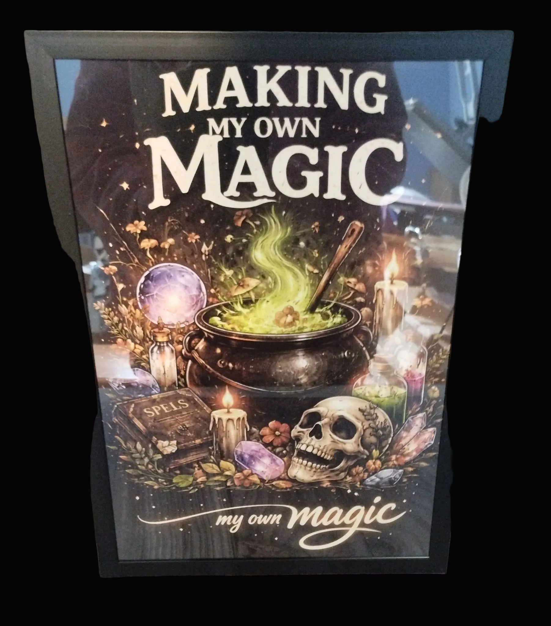 Framed poster with a mystical design featuring a cauldron, skull, and text 'Making My Own Magic'.