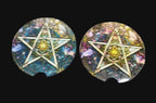 Two car coasters with pentagram designs on a wooden surface