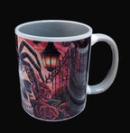 Mug with a dark, artistic design featuring roses and a lantern on a wooden surface.